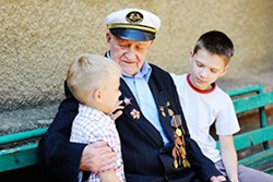 grandfather in uniform sitting on bench with grandchildren