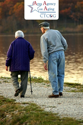 elderly couple walking along water